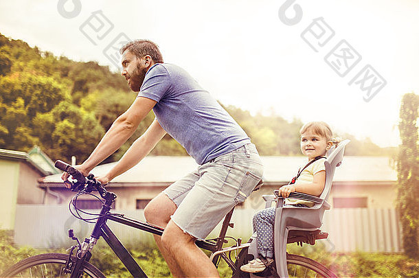 年轻的父亲女儿自行车绿色阳光明媚的公园