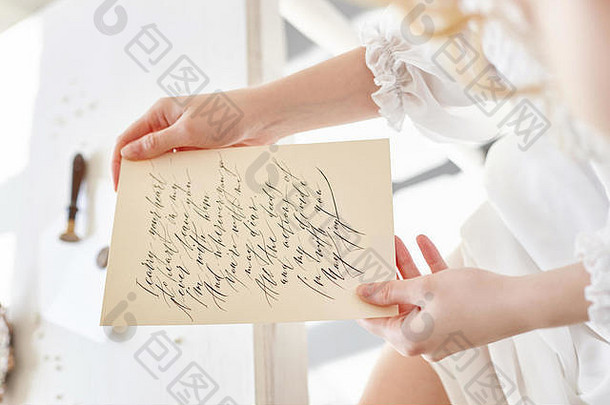 女孩写信亲爱的男人。坐着首页表格白色光衣服纯度是清白的卷曲的金发女郎浪漫的美丽的