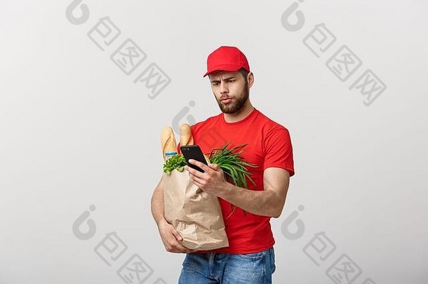 交付概念英俊的高加索人杂货店交付快递男人。红色的统一的杂货店盒子新鲜的水果蔬菜