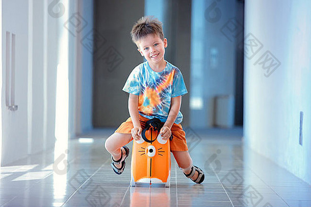 可爱的年男孩笑着说坐着手提箱机场