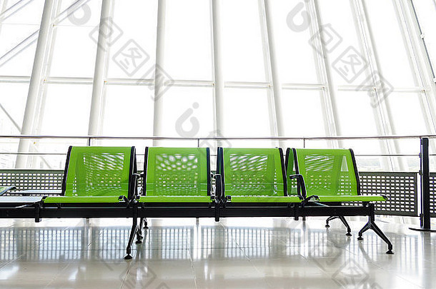 板凳上绿色座位离开大厅机场巨大的窗户背景