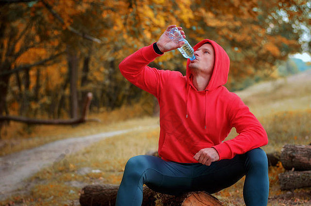 年轻的运动跑步者红色的体育夹克罩黑色的体育运动导管喝水瓶慢跑色彩斑斓的秋天前