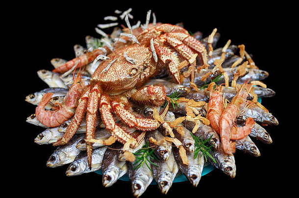 大多毛的煮熟的蟹坐在堆干咸鱼礼物花束黑色的背景