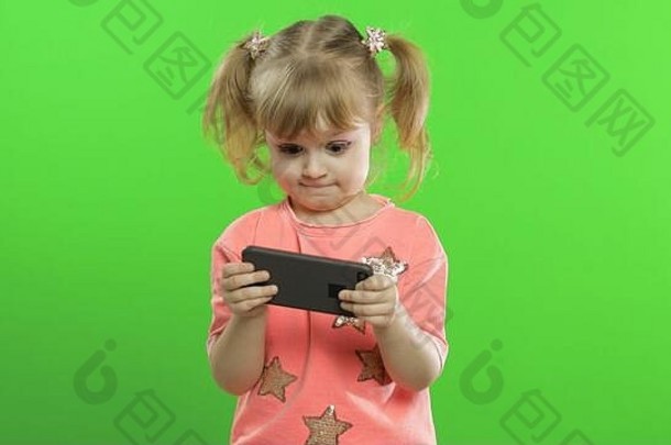女孩智能手机肖像孩子粉红色的上衣智能手机发短信玩孩子热情地玩游戏移动电话绿色浓度关键背景键控