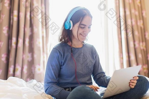 十几岁的女孩耳机移动PC视频聊天床上