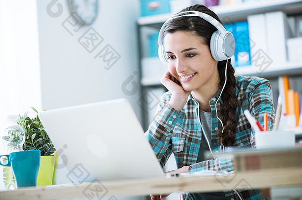 十几岁的微笑女孩移动PC穿耳机技术休闲概念