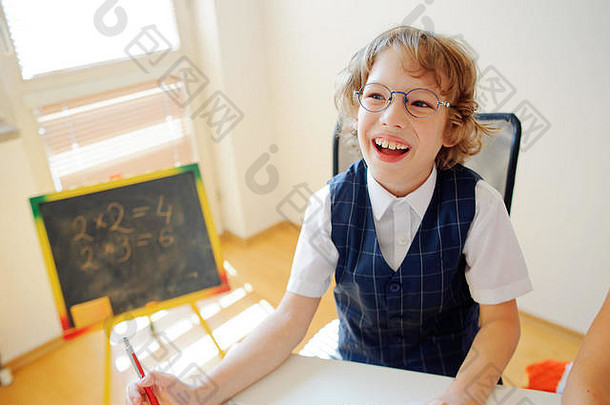 快乐的学生戴眼镜的坐在学校桌子上弟子小学学校手男孩球笔