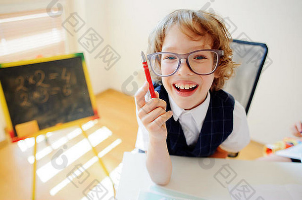 有趣的学生戴眼镜的坐在学校桌子上弟子小学学校手男孩球笔