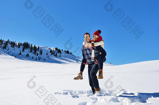 年轻的夫妇有趣的雪快乐男人。山给肩扛骑微笑女朋友