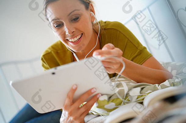 女人连接平板电脑耳机看电影