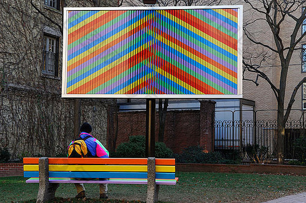 男人。板凳上看广告牌艺术安装城市parkette多伦多