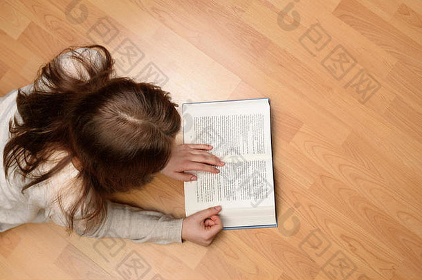 前视图年轻的女人说谎地板上阅读书