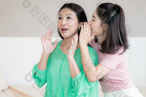 亚洲十几岁的女孩窃窃私语母亲的耳朵支出时间首页妈妈。惊讶