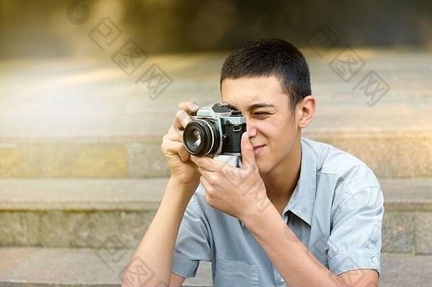 年轻的男人。采取照片相机在户外城市步骤微笑组成集中拍摄