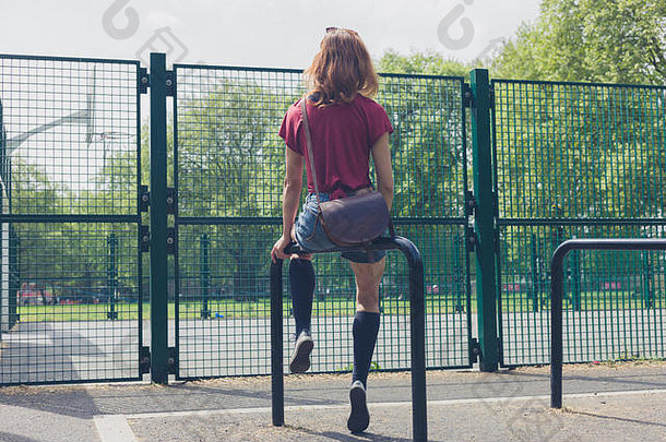 年轻的女人坐着铁路公园篮球法院夏天一天