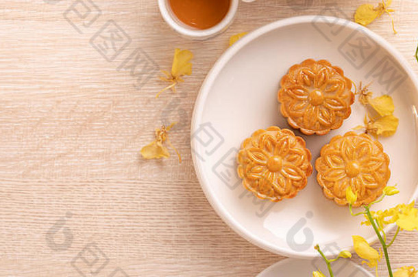 美味的月亮蛋糕中秋节日明亮的木表格概念节日下午茶装饰黄色的花前视图平躺