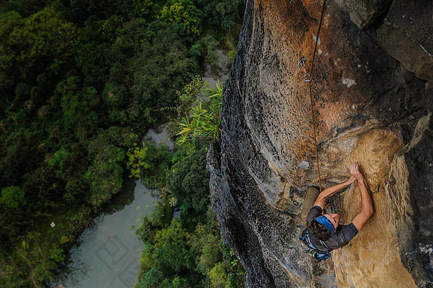 男人。岩石攀爬桂林圆锥形的帽子高角视图yangshuo广西中国