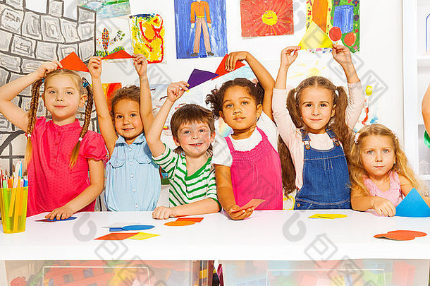 集团男孩女孩坐着表格持有颜色纸板形状幼儿园房间