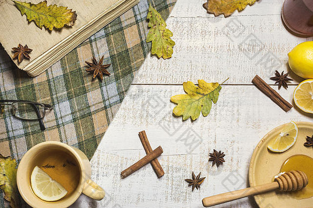 杯热茶柠檬蜂蜜香料书秋天叶子木背景前视图秋天概念背景