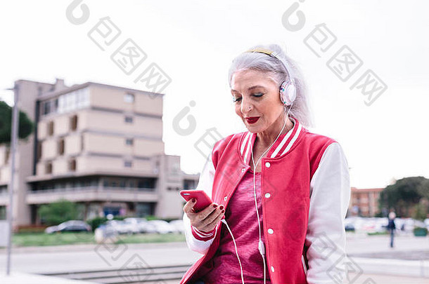 成熟的女人棒球夹克听耳机智能手机