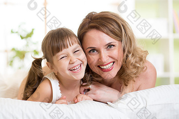 肖像快乐的妈妈。女儿说谎床上卧室