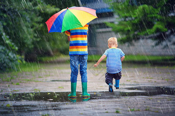 孩子们走长筒靴水坑多雨的天气