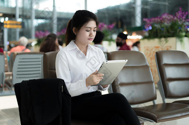 亚洲年轻的女人乘客机场平板电脑电脑等待飞行终端机场