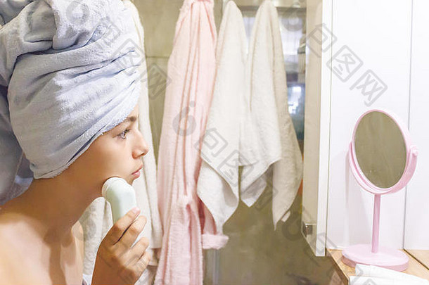 年轻的美丽的青少年女孩毛巾使面部按摩