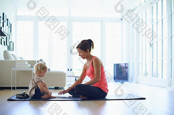 中期成人妈妈。蹒跚学步的女儿练习瑜伽生活房间