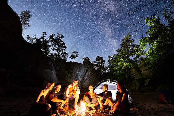 快乐朋友徒步旅行者休息篝火营照亮旅游帐篷晚上背景美丽的晚上布满星星的天空完整的星星乳白色的山岩石