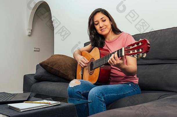 女人坐着沙发首页采取吉他教训在线在线学习概念