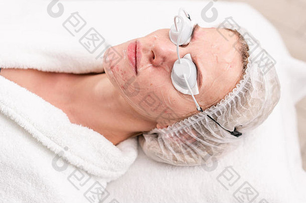 肖像年轻的女人病人反痤疮光疗专业设备美丽的女人照片复兴过程脸皮肤治疗化妆品诊所
