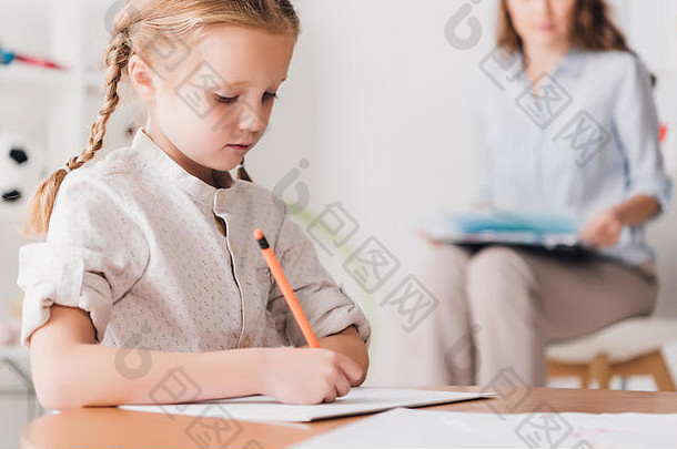 集中孩子画心理学家剪贴板坐着模糊背景