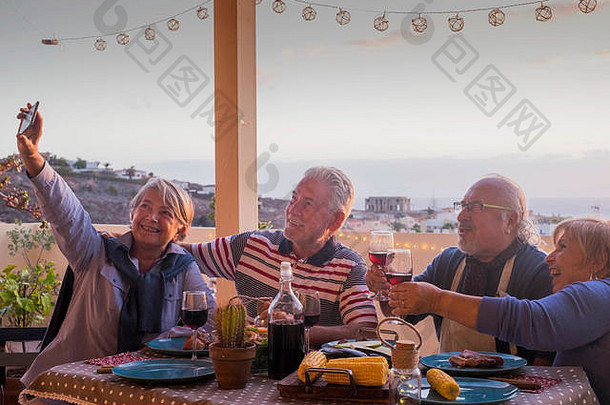 集团成年人朋友上了年纪的退休有趣的采取图片自拍晚餐户外阳台屋顶庆祝