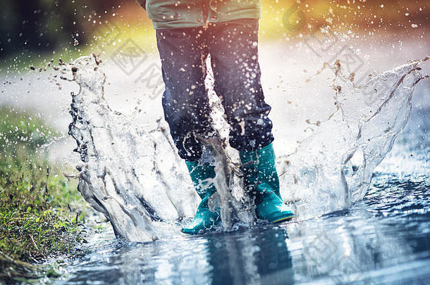 孩子走长筒靴水坑多雨的天气