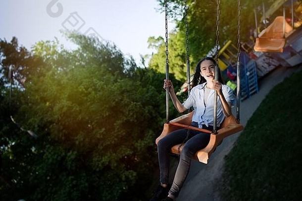 快乐孩子十几岁的女孩骑链旋转木马摇摆不定的娱乐公园