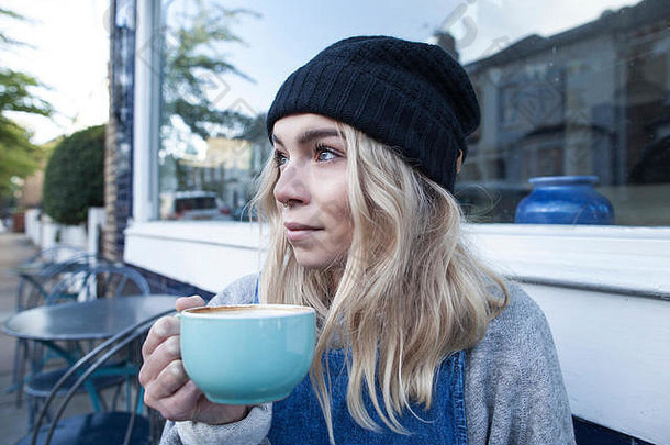 年轻的女人坐着咖啡馆喝杯茶