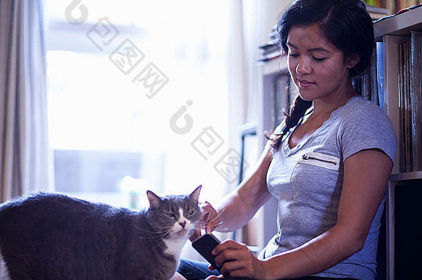 年轻的女人持有细胞电话抚摸猫