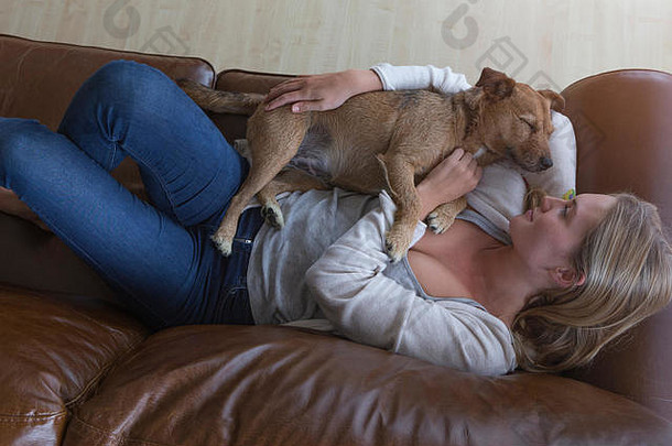 爱丽儿视图女人拥抱宠物狗皮革沙发
