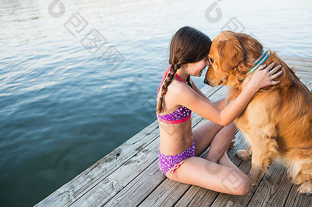 年轻的女孩金寻回犬狗坐着码头
