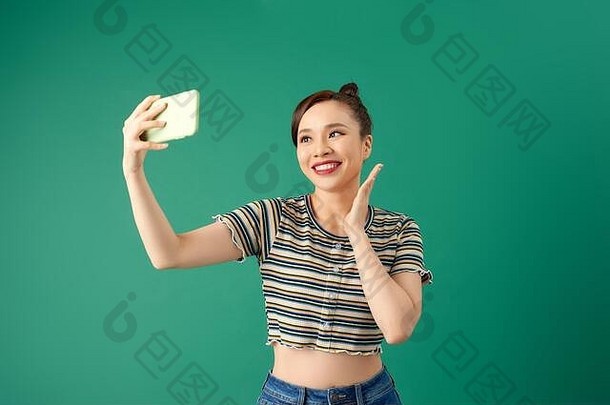 肖像年轻的亚洲女使自拍照片智能手机postitive表达式绿色背景