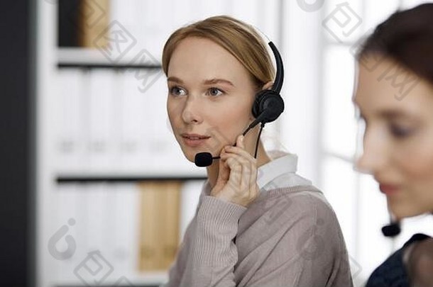 友好的女商人会说话的耳机办公室调用中心多样化的人集团业务