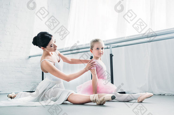 可爱的芭蕾舞女演员粉红色的图图坐着伸展运动培训芭蕾舞老师工作室