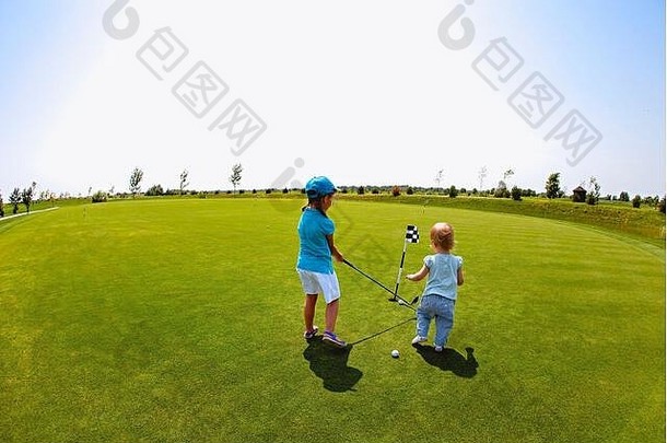 回来视图女孩蹒跚学步的兄弟姐妹玩高尔夫球绿色草坪上阳光明媚的夏天一天