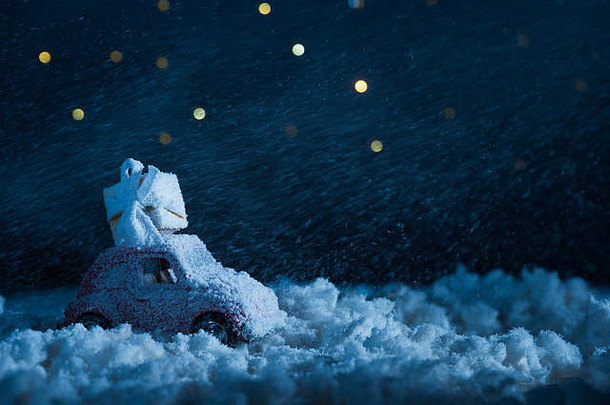 特写镜头拍摄玩具车礼物盒子站雪晚上布满星星的天空圣诞节概念