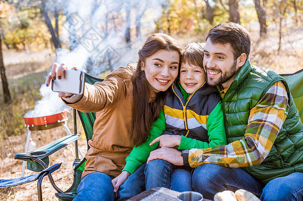 快乐微笑家庭野餐有趣的采取自拍秋天公园