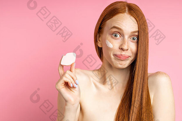 困惑年轻的红色头发的人女人相机困惑表达式持有化妆品海绵形状嘴唇耸肩膀皮肤护理而是大世界