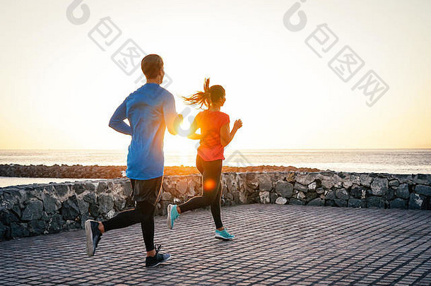 健康年轻的夫妇慢跑海洋华丽的日落人工作海滩的关系体育运动生活方式概念