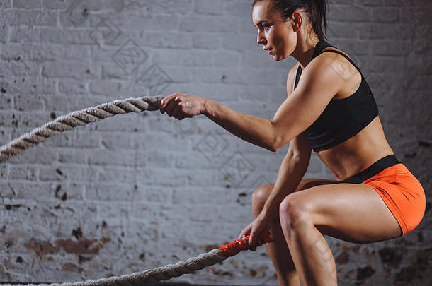 强大的女人锻炼战斗绳子健身房