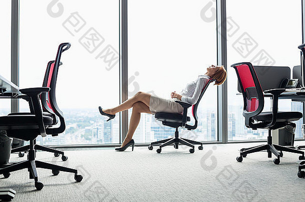 完整的长度一边视图年轻的女商人倾斜回来椅子办公室